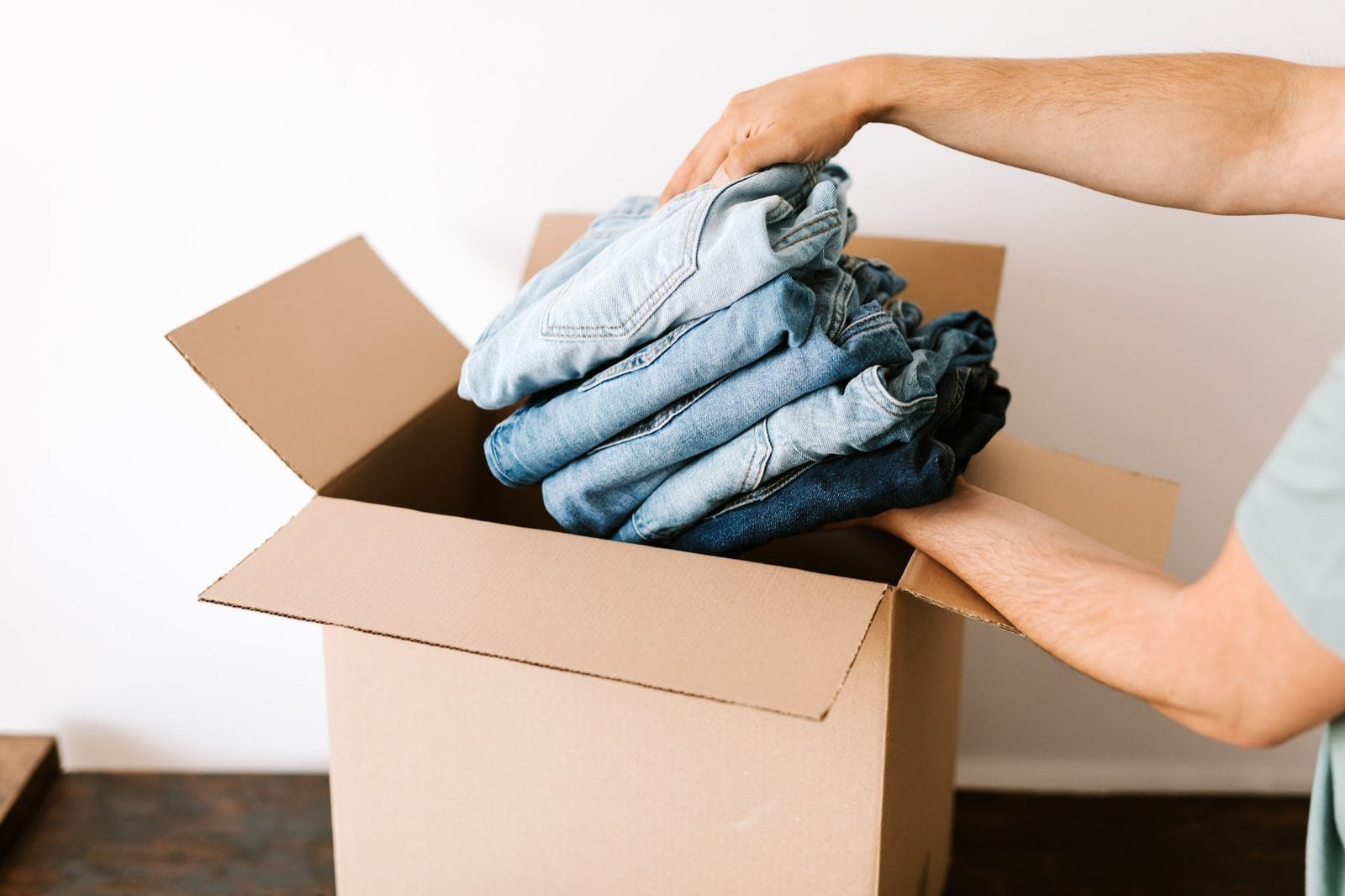 Persona guardando ropa usada en una caja para venderla en apps de segunda mano